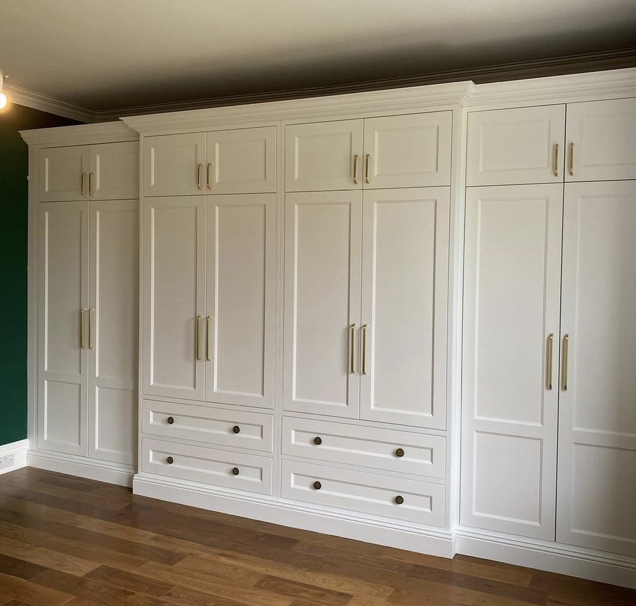 A full wall of fitted cupboards sprayed off-white with brushed handles