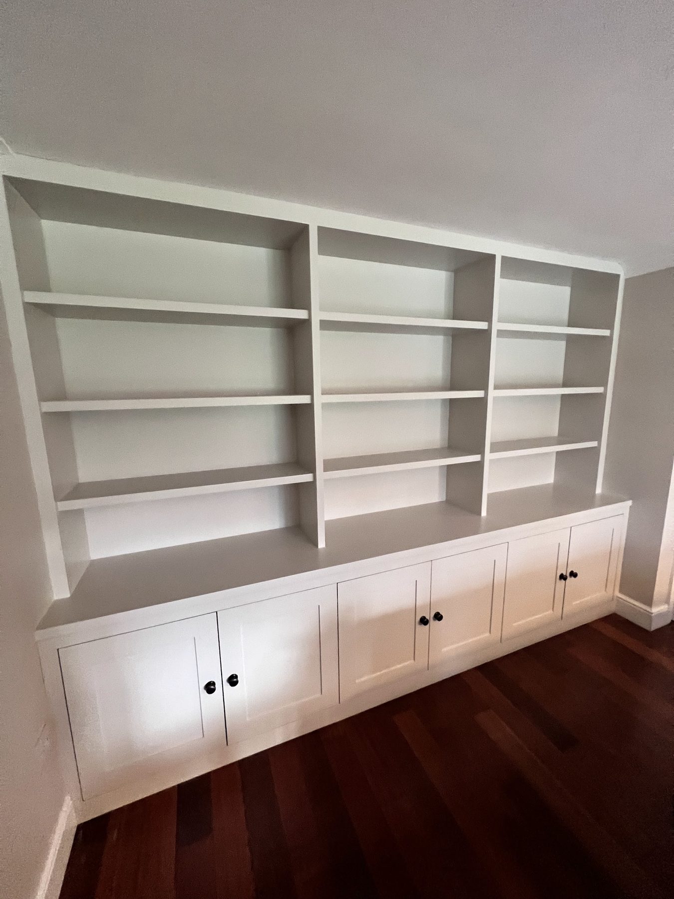 A built-in bookcase and cupboards sprayed white