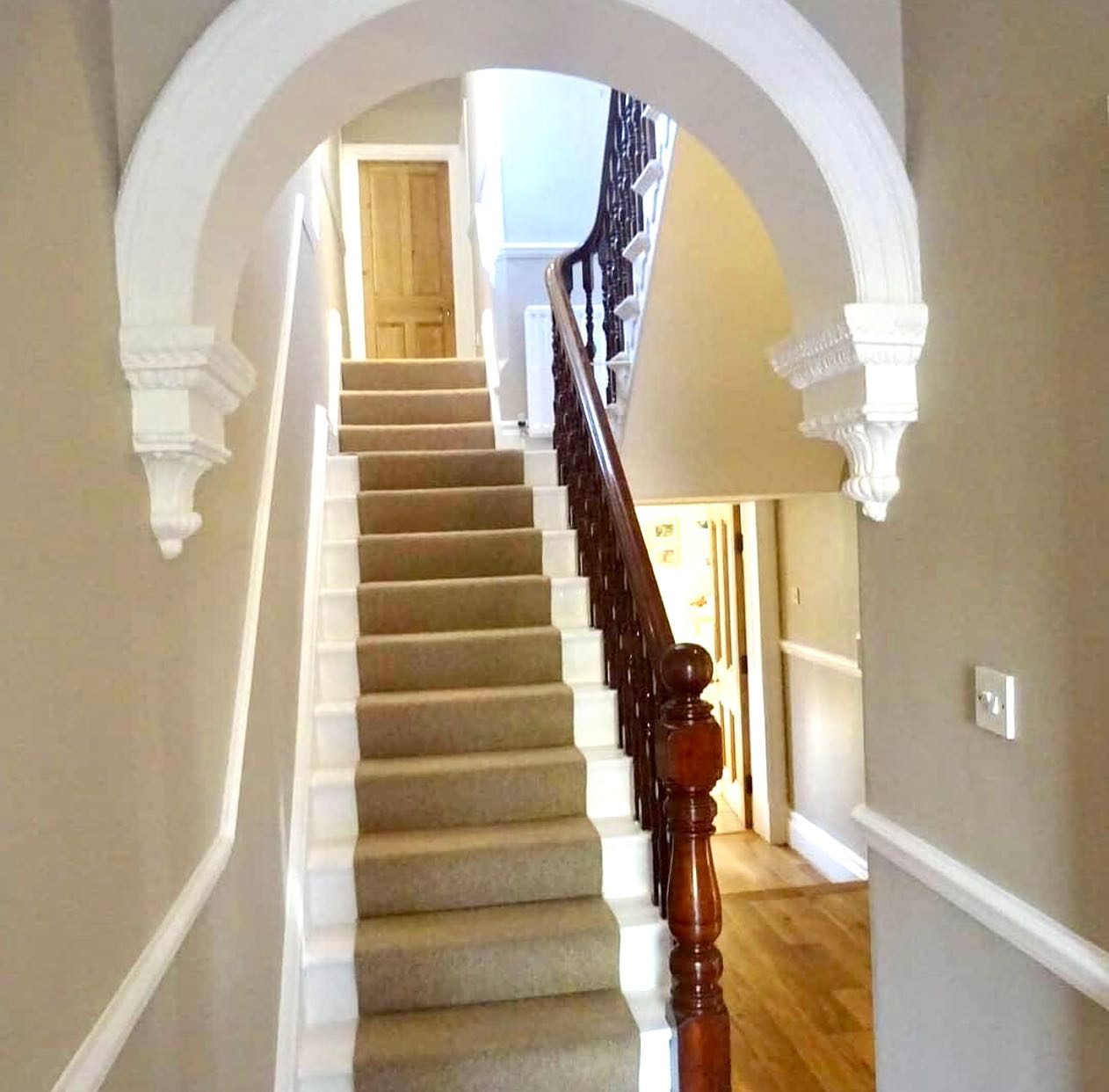 A decorated hallway and staircase with a white arch