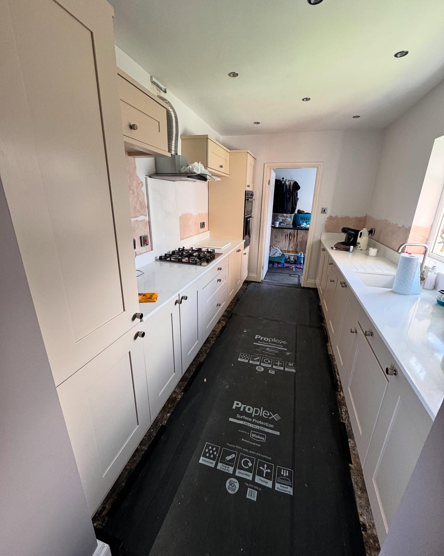 A kitchen mid-respray with protective sheeting down on the floor